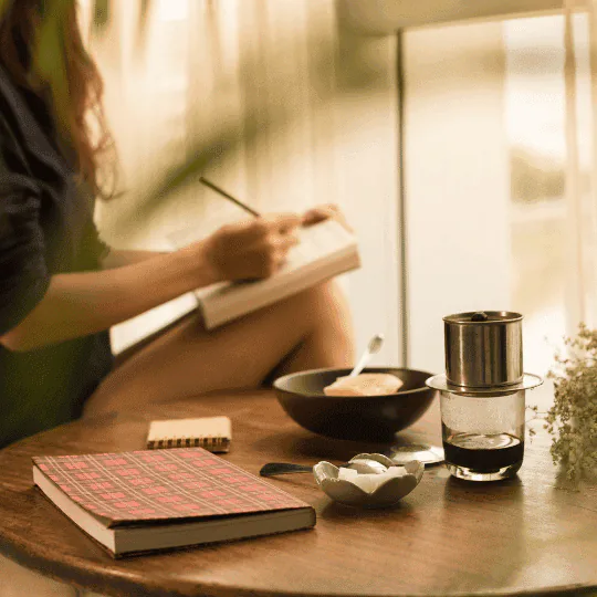 A person journaling by hand in a bright, lived-in room