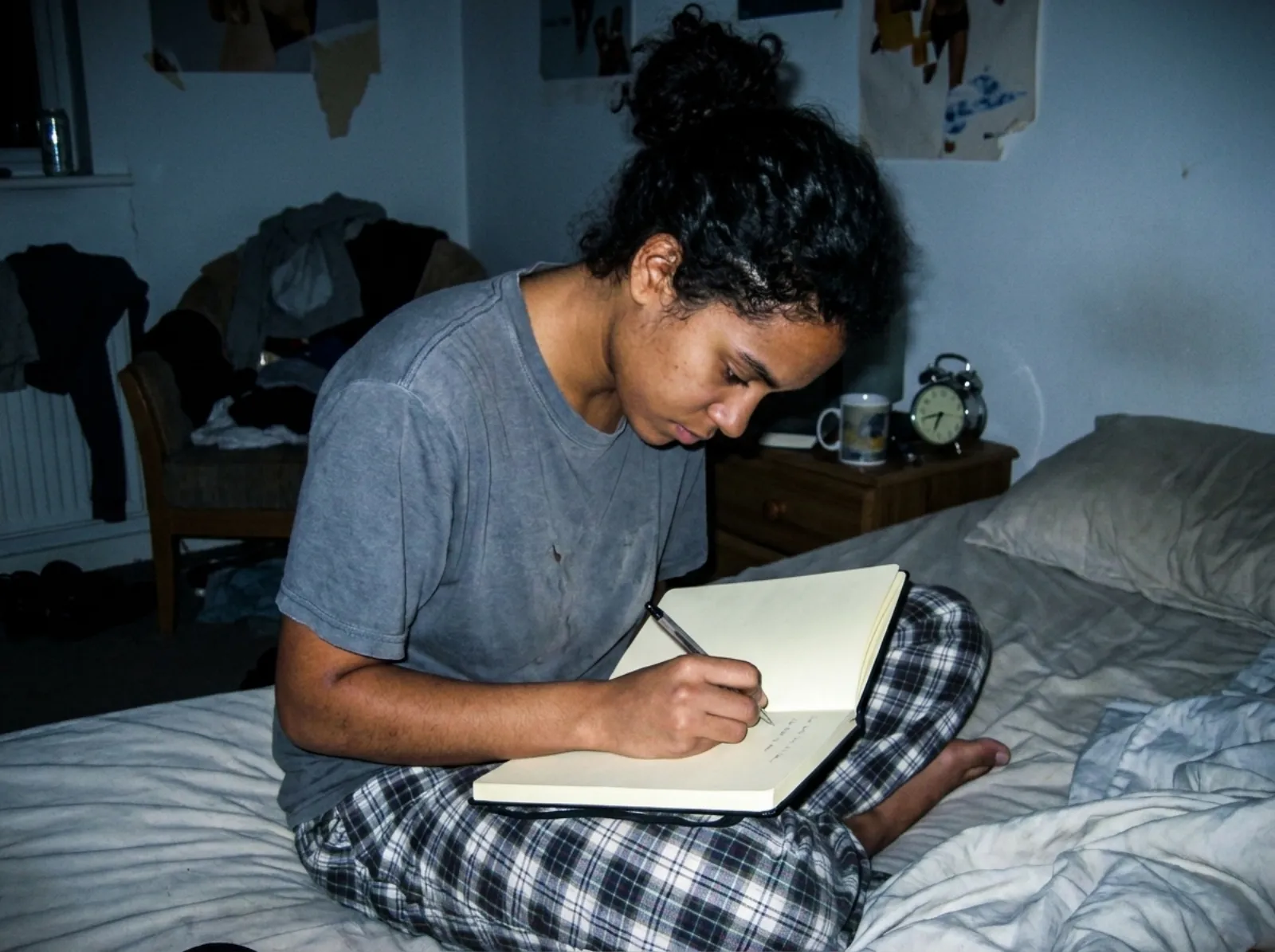 Person journaling by hand at a bedroom window in early morning light